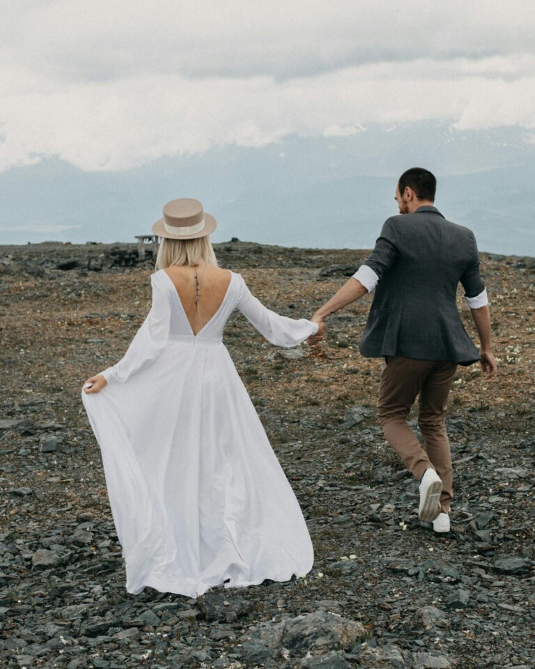 Anonymous groom and bride walking on rocky land